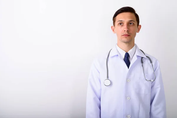 Estudio de tiro de joven guapo médico hombre pensando mientras busca —  Fotos de Stock