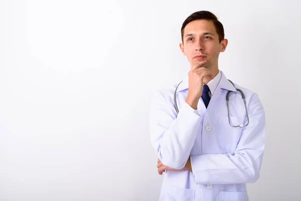 Estúdio tiro de jovem bonito homem médico pensando contra branco — Fotografia de Stock