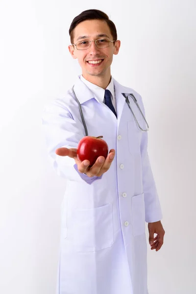 Strzał studio lekarz młody człowiek szczęśliwy uśmiechający się dając czerwony — Zdjęcie stockowe