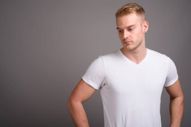 Sarı saçlı, gri arka planda genç yakışıklı bir adam.