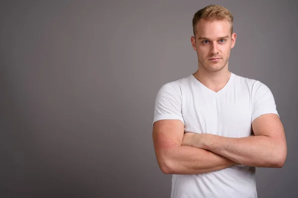 Jovem homem bonito com cabelo loiro contra fundo cinza — Fotografia de Stock