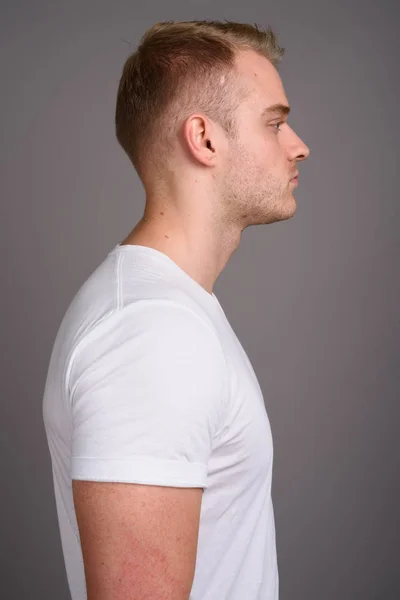 Young handsome man with blond hair against gray background — Stock Photo, Image