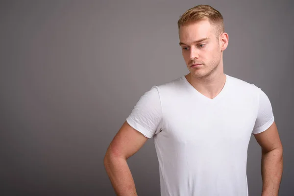 Young handsome man with blond hair against gray background