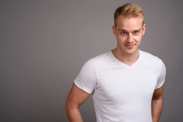 Joven hombre guapo con el pelo rubio sobre fondo gris — Foto de Stock