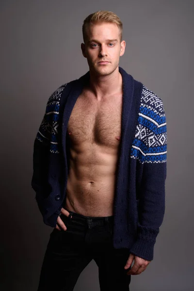 Sarı saçlı, gri arka planda genç yakışıklı bir adam.