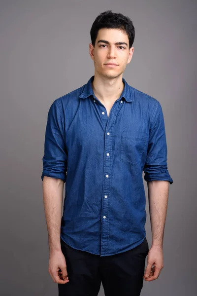 Portrait of young handsome businessman against gray background — Stock Photo, Image