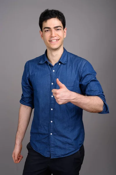 Portrait of young handsome businessman against gray background — Stock Photo, Image