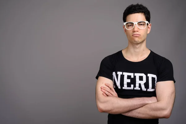Joven hombre nerd guapo con anteojos sobre fondo gris — Foto de Stock