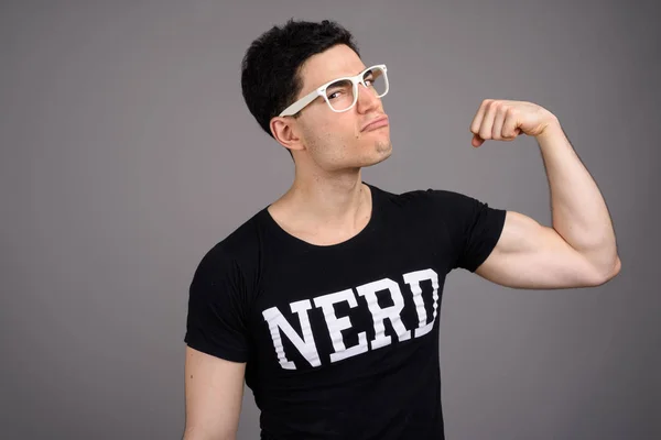 Jovem nerd bonito homem com óculos contra fundo cinza — Fotografia de Stock