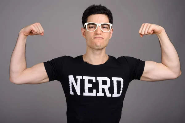 Jovem nerd bonito homem com óculos contra fundo cinza — Fotografia de Stock