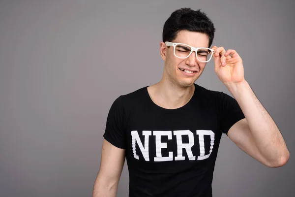 Young handsome nerd man with eyeglasses against gray background — Stock Photo, Image