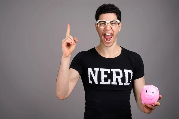 Young handsome nerd man with eyeglasses against gray background — Stock Photo, Image