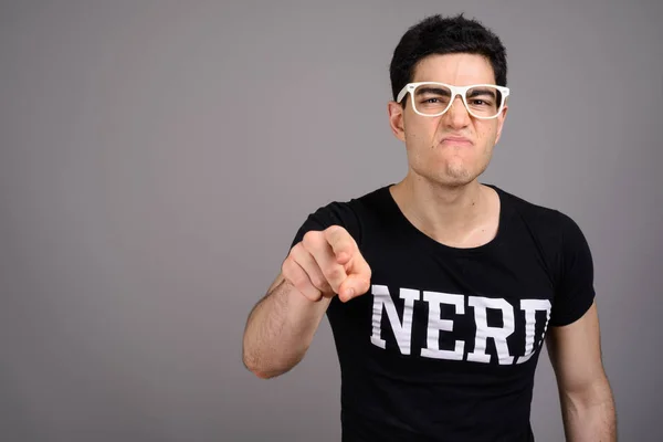 Jovem nerd bonito homem com óculos contra fundo cinza — Fotografia de Stock