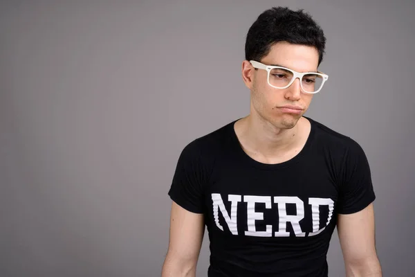 Young handsome nerd man with eyeglasses against gray background — Stock Photo, Image