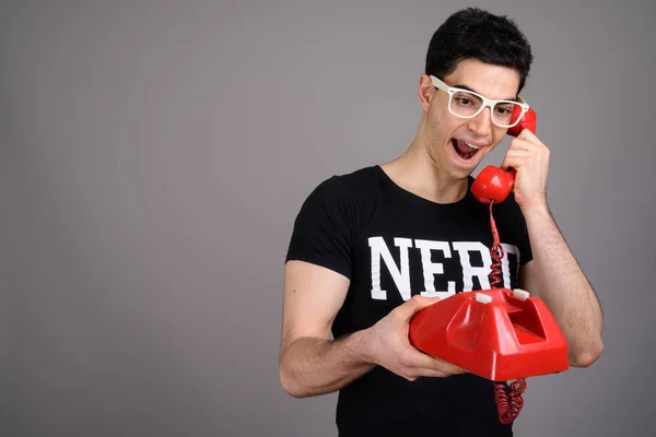 Young handsome nerd man with eyeglasses against gray background — Stock Photo, Image