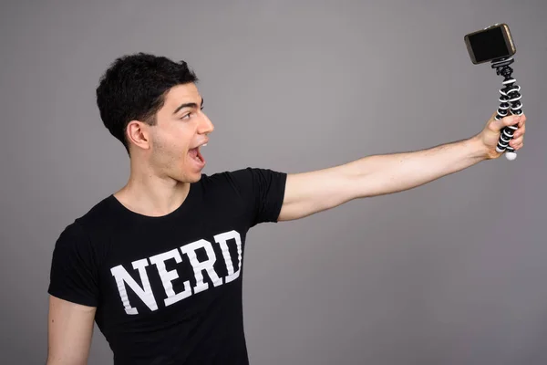Young handsome nerd man against gray background — Stock Photo, Image
