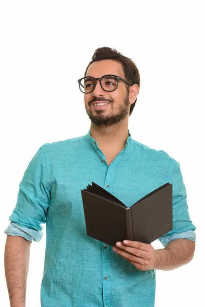 Jeune homme indien heureux tenant livre tout en pensant — Photo