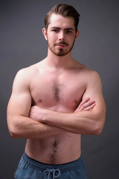 Молодий красивий бородатий чоловік без сорочки на сірому фоні — стокове фото