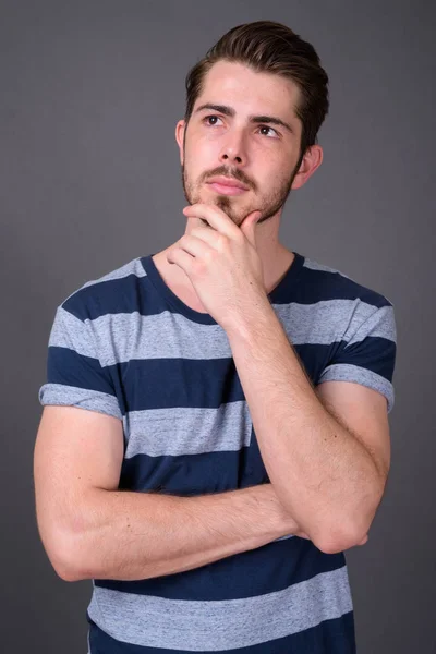 Junger gutaussehender bärtiger Mann vor grauem Hintergrund — Stockfoto