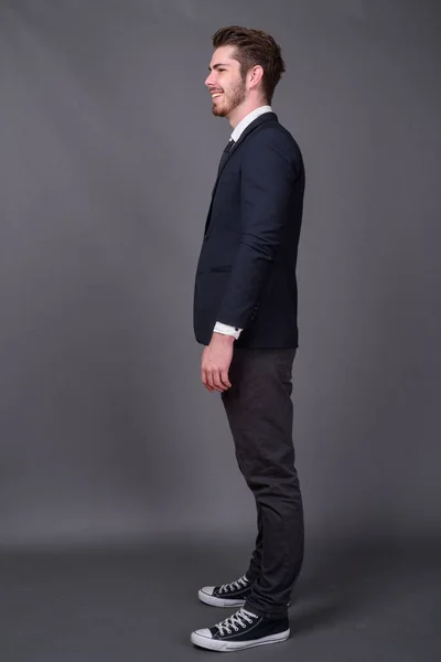 Junger gutaussehender bärtiger Geschäftsmann mit grauem Hintergrund — Stockfoto