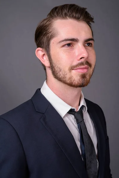 Young handsome bearded businessman against gray background — Stock Photo, Image