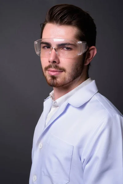 Giovane bello barbuto uomo medico indossa occhiali protettivi aga — Foto Stock