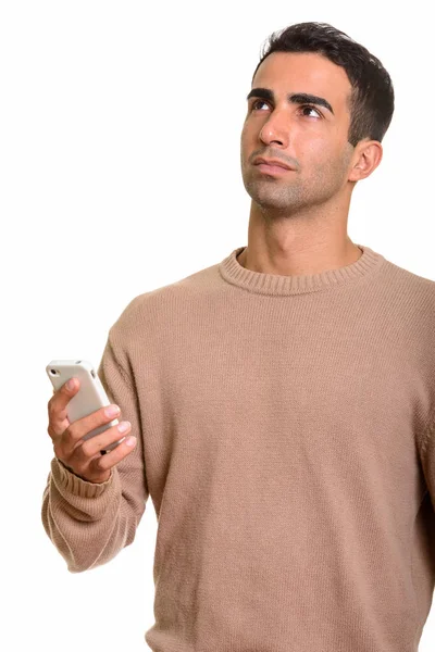 Jovem bonito homem persa usando telefone celular enquanto pensa — Fotografia de Stock