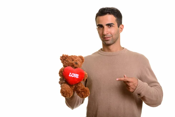 Молодой красивый персидский мужчина держит плюшевого мишку с символом любви — стоковое фото