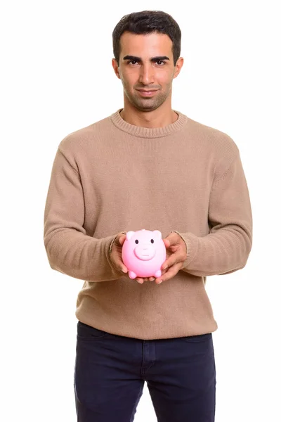 Portrait of young handsome Persian man with piggy bank — Stock Photo, Image