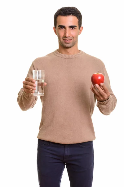 Retrato de un joven guapo sosteniendo un vaso de agua y manzana — Foto de Stock