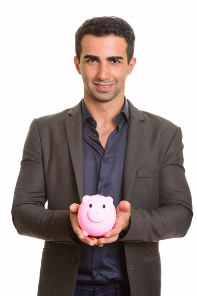 Persian businessman holding piggy bank against white background — Stock Photo, Image
