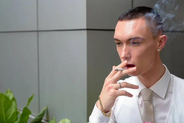 Young androgynous homosexual LGTB businessman smoking cigarette — Stock Photo, Image