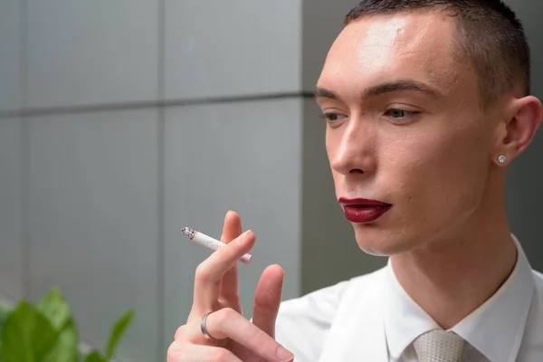 Молодой андрогинный гомосексуальный бизнесмен LGTB курит сигарету — стоковое фото