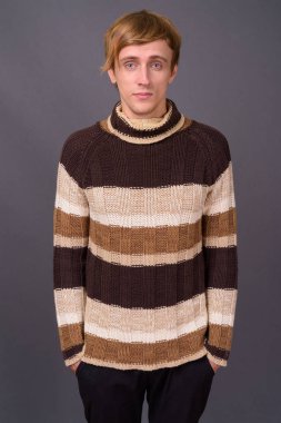 Sarı saçlı, gri arka planda genç yakışıklı bir adam.