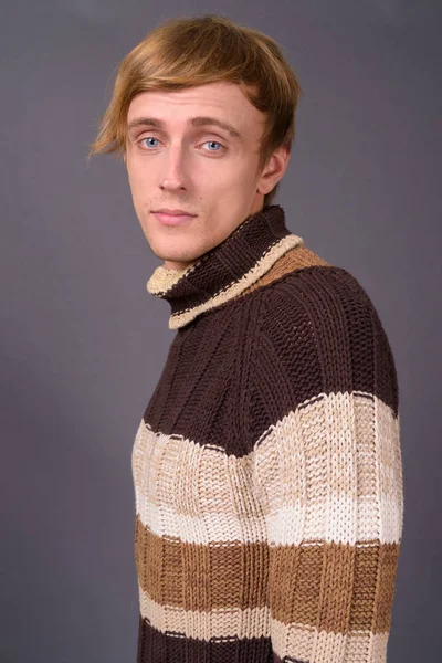 Junger schöner Mann mit blonden Haaren vor grauem Hintergrund — Stockfoto