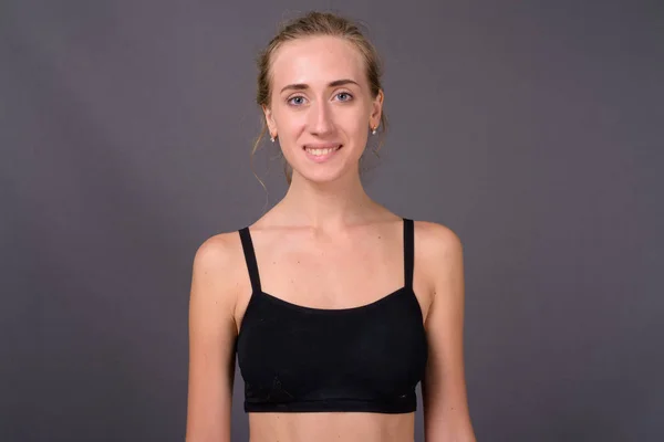 Ung vacker kvinna redo för gym mot grå bakgrund — Stockfoto