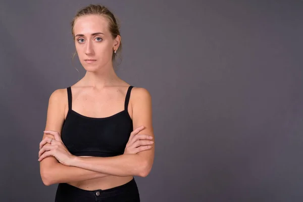 Jovem bela mulher pronta para ginásio contra fundo cinza — Fotografia de Stock