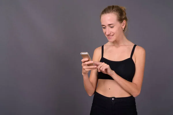 Young beautiful woman ready for gym against gray background — Stock Photo, Image