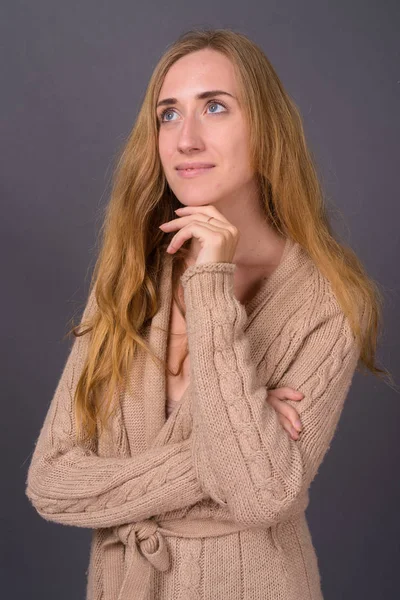 Jovem mulher bonita com cabelo loiro contra fundo cinza — Fotografia de Stock