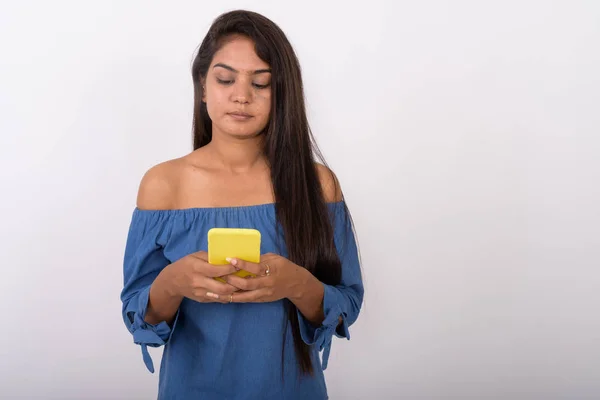 Studio shot of young Indian woman using mobile phone against whi — Stock Photo, Image