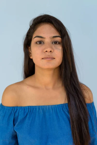 Ansikte av unga confidentindian kvinna mot blå bakgrund — Stockfoto