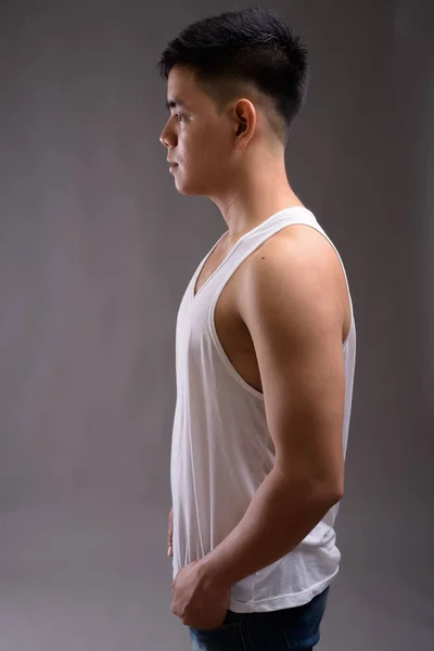 Jonge knappe Aziatische man dragen tank boven tegen de grijze pagina — Stockfoto
