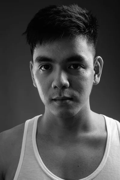 Joven guapo asiático hombre usando camiseta sin mangas contra gris backgroun —  Fotos de Stock
