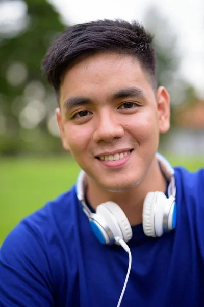 Portrait of young handsome Asian man relaxing at the park in Bangkok, Thailand