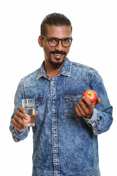 Młody szczęśliwy Indianin trzyma czerwone jabłko i szklankę wody — Zdjęcie stockowe