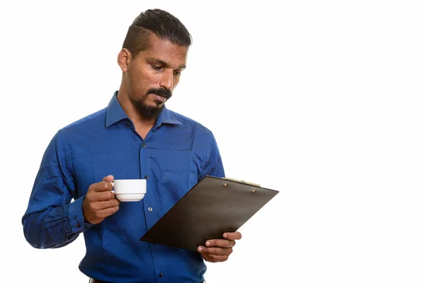 コーヒーを押しながらクリップボードを読んで若いインドの実業家 — ストック写真