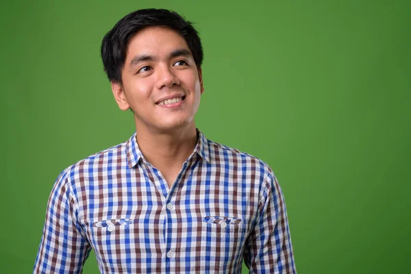 Молодой красивый филиппинский мужчина на зеленом фоне — стоковое фото