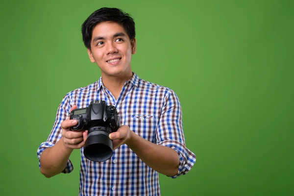 Fiatal jóképű filippínó férfi zöld háttér — Stock Fotó