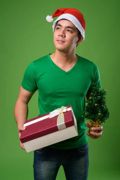 Jovem filipino bonito homem pronto para o Natal contra ba verde — Fotografia de Stock