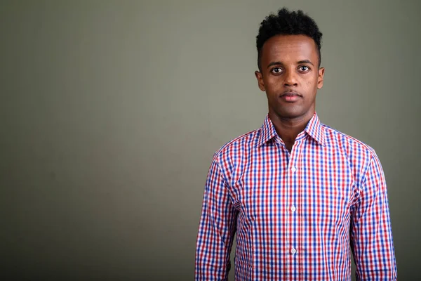 Jonge knappe Afrikaanse zakenman tegen gekleurde achtergrond — Stockfoto